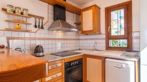 Una cocina con estufa, horno, lavavajillas y ventana con vistas al verdor.
