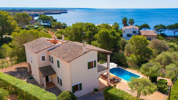 Una casa a due piani con piscina, immersa nel verde e affacciata sull'acqua.