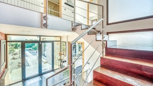 A modern interior with a staircase connecting two floors, large glass doors leading to an outdoor area, and a view of the sky. - Amazing home in Campos with private swimming pool, can be inside or outside (Campos)