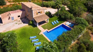 Une villa avec piscine, un patio doté de chaises longues et un bâtiment en pierre.