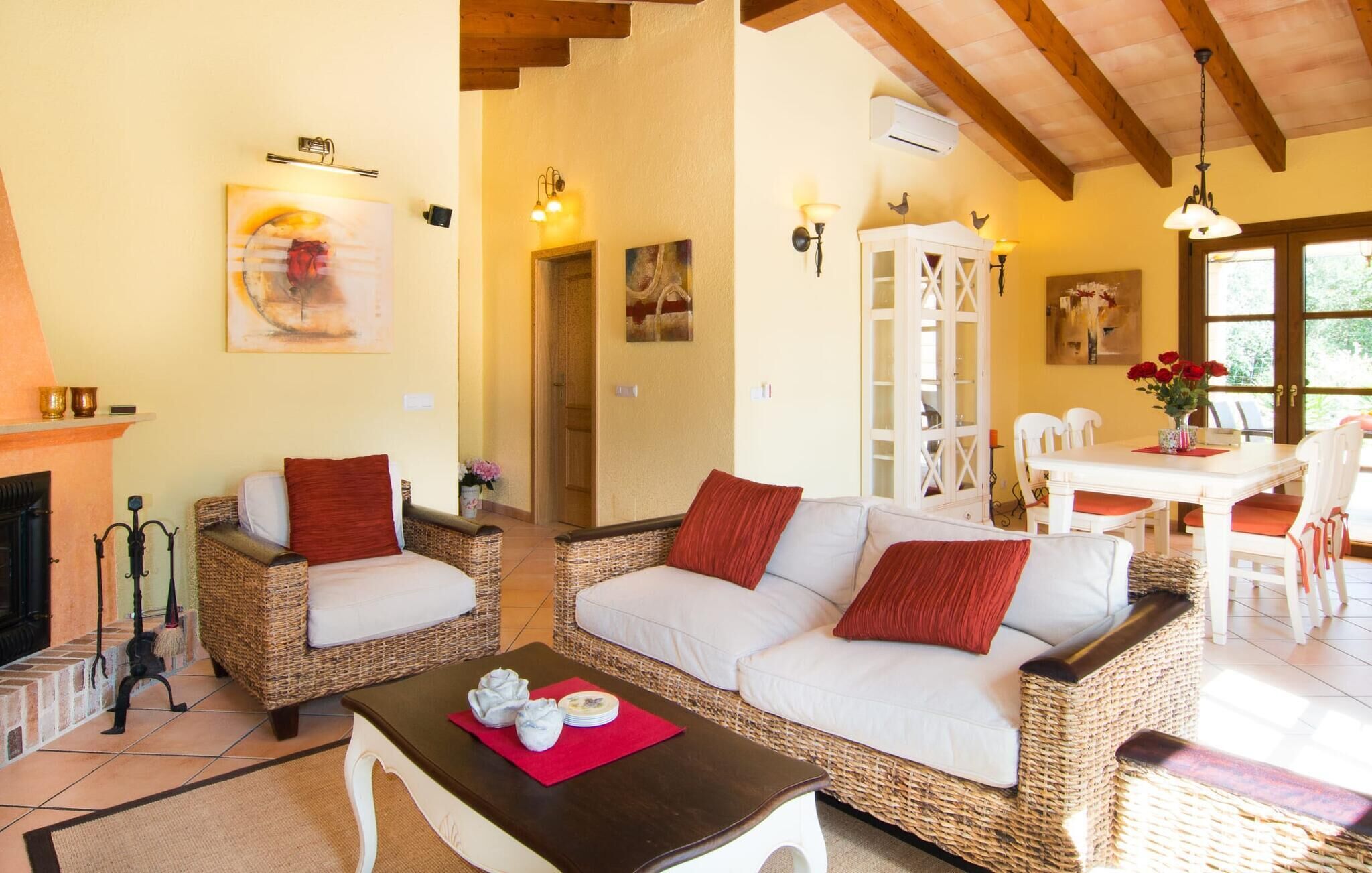 A cozy living room with wicker furniture, a fireplace, and a dining area with a table and chairs.