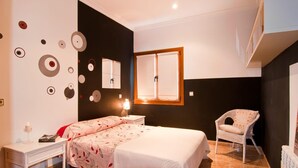 Ein Schlafzimmer mit einem Bett, einem Sessel, einem Schreibtisch und einem Spiegel.