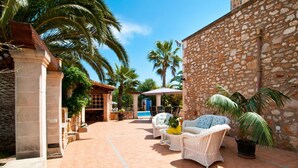 Un patio con muebles de mimbre, una piscina y muros de piedra.