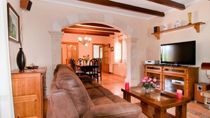Una sala de estar con un sofá de cuero marrón, un mueble de madera para entretenimiento y un televisor de pantalla plana.