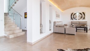 Un amplio salón con una escalera, un conjunto de sofás y un cuadro abstracto grande en la pared.