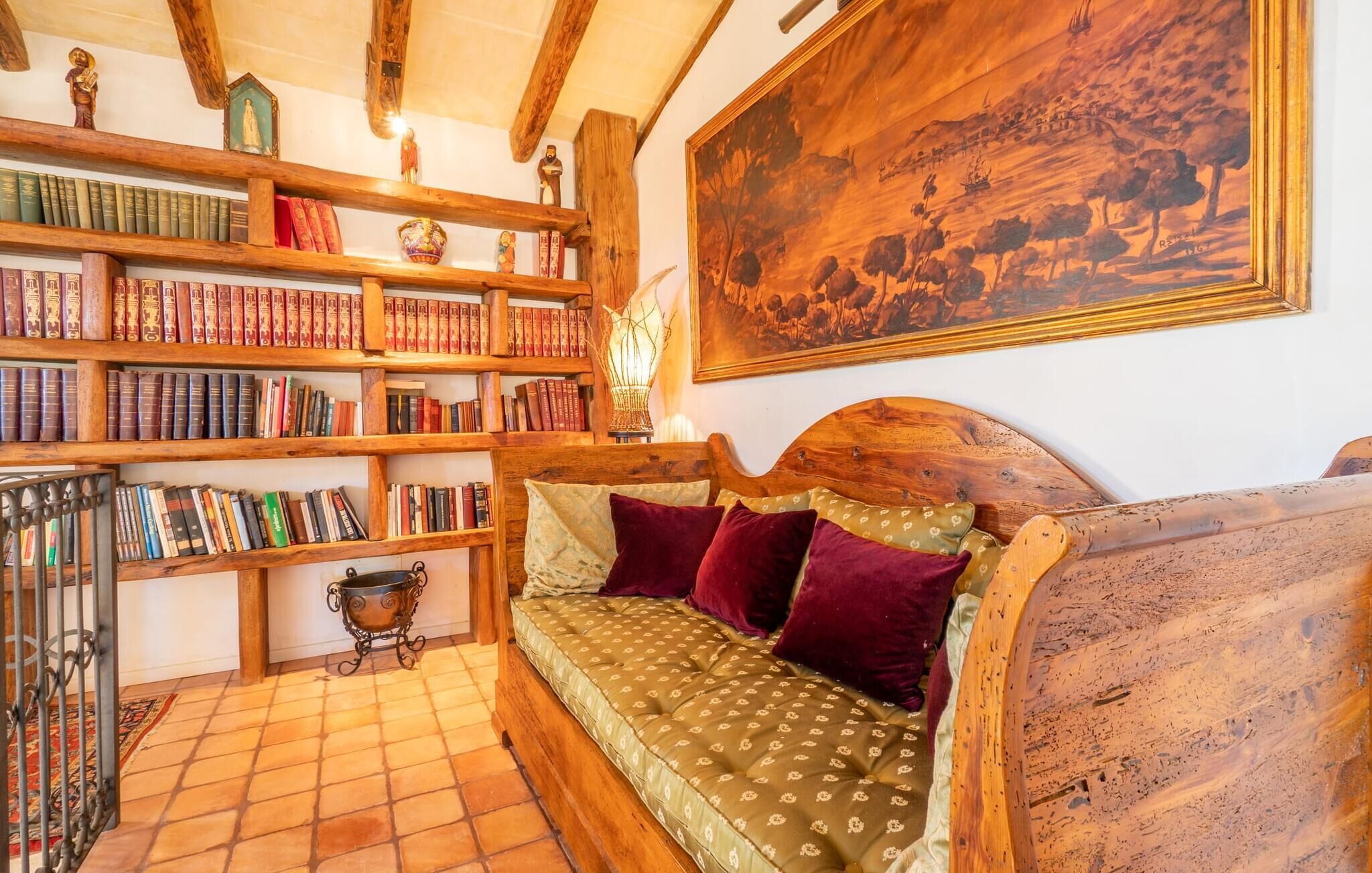 Um quarto acolhedor com um banco de madeira, uma estante repleta de livros e um quadro grande na parede.