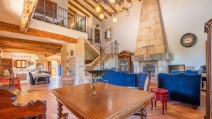 A spacious living area with a wooden dining table, blue sofas, a stone fireplace, and a staircase leading to an upper level. - Awesome home in Campos with private swimming pool, can be inside or outside (Campos)