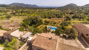 Eine Villa mit Swimmingpool, umgeben von Olivenhainen und Hügeln.