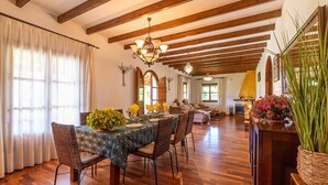 Ein Essbereich mit Holztisch, Korbstühlen und einer Chandelier.