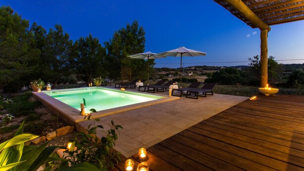 A pool area with lounge chairs and umbrellas, surrounded by greenery and a wooden deck. - Nice home in Sant Llorenc with private swimming pool, can be inside or outside (Sant Llorenc)