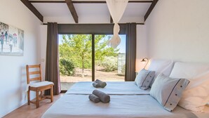 Un dormitorio con una cama grande, una silla y vistas al exterior.