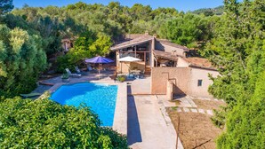 Una casa con piscina, rodeada de exuberante follaje y árboles.