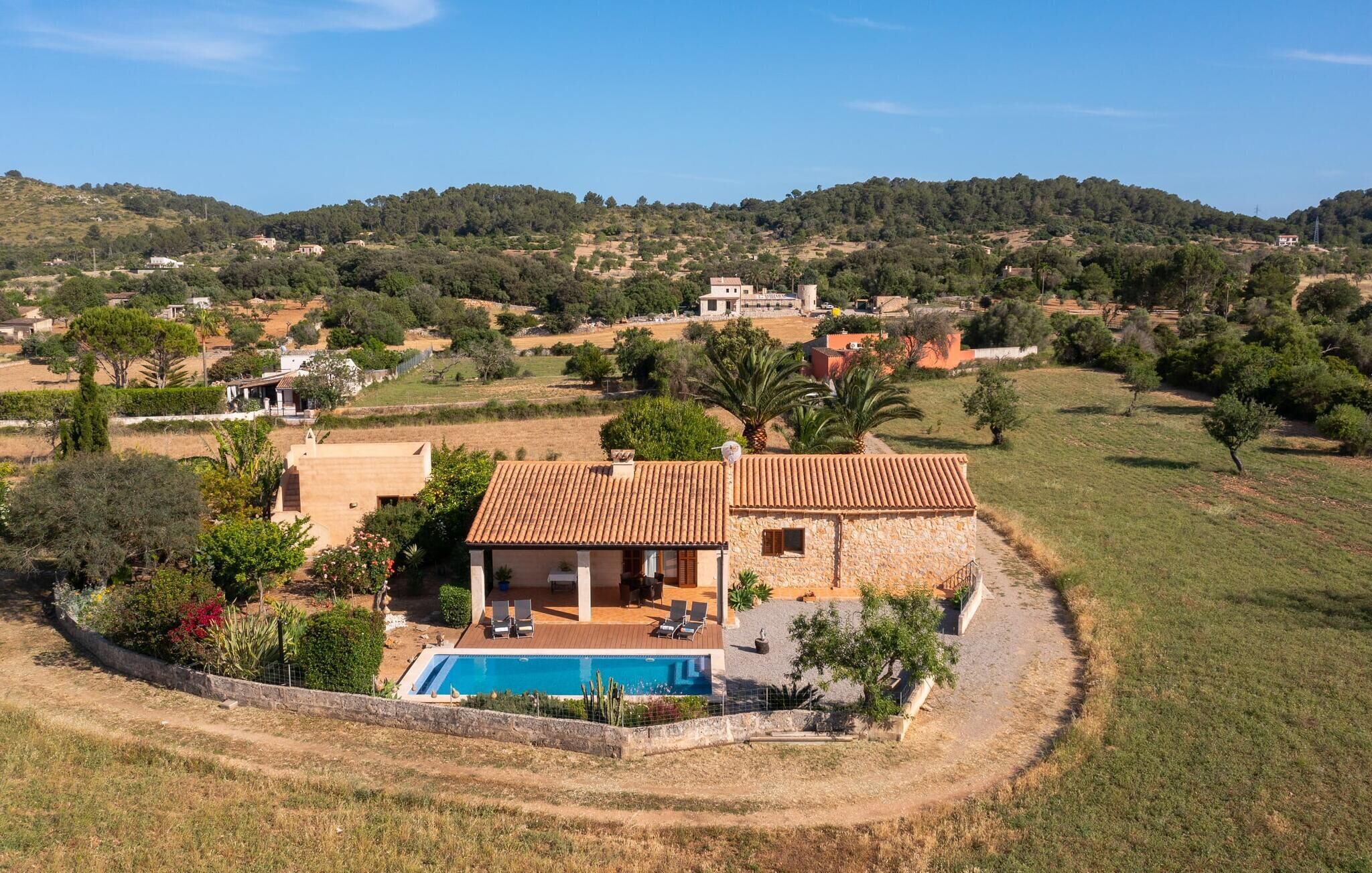 A villa with a swimming pool, surrounded by a garden and a view of the countryside.