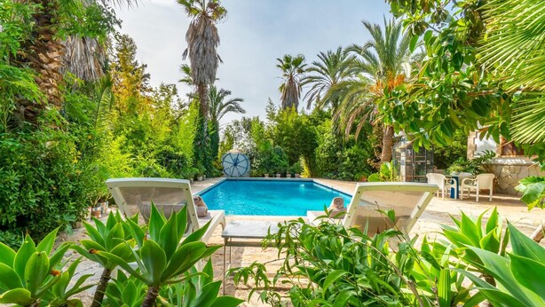 A swimming pool surrounded by lush greenery and two lounge chairs. - Amazing home in Consell with private swimming pool, can be inside or outside (Consell)