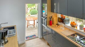 A modern kitchen with a glass door leading to a patio, a wooden table, and a small dining area. - Awesome home in Inca with private swimming pool, can be inside or outside (Inca)