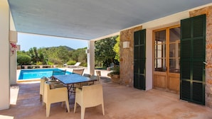 Eine Terrasss mit Pool, Tisch und Stühlen und Blick auf die umliegende Natur.
