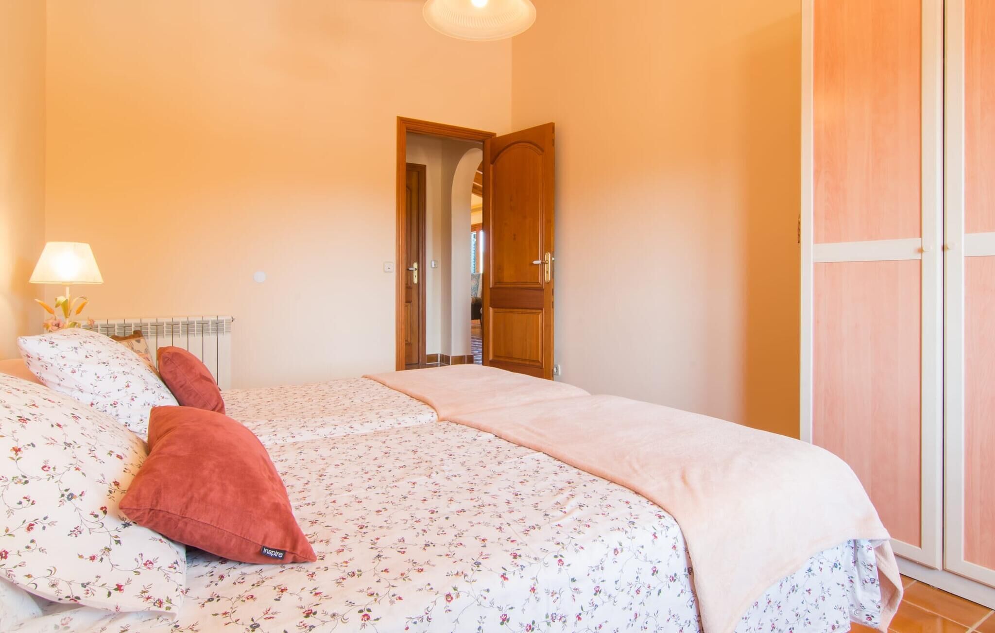 A bedroom with a bed, a nightstand, a lamp, and a wardrobe.