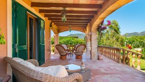A covered outdoor seating area with wicker furniture, a table, and a decorative vase. - Beach front home in Port Verd (Port Verd)
