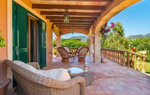 A covered outdoor seating area with wicker furniture, a table, and a decorative vase. - Beach front home in Port Verd (Port Verd)