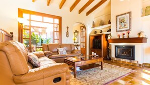 A cozy living room with a leather sofa, a coffee table, and a fireplace. - Beach front home in Port Verd (Port Verd)