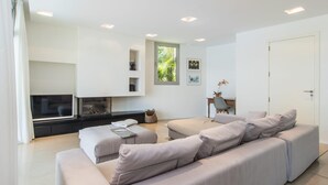 Een moderne woonkamer met een grote L-zitsbank, een flatscreen televisie en een open haard.
