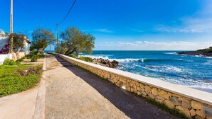 A coastal road with a stone wall, a clear blue sky, and the ocean. - Amazing home in Cala Ratjada with WiFi (Cala Ratjada)