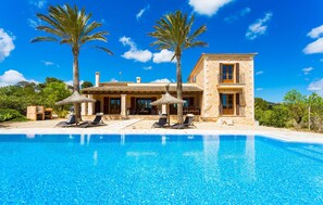 A two-story stone building with a swimming pool, palm trees, and outdoor seating. - Beautiful home in Portocolom (Portocolom)