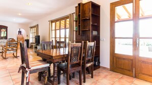 Un comedor con una mesa y sillas de madera, una estantería y un ventanal con vistas.