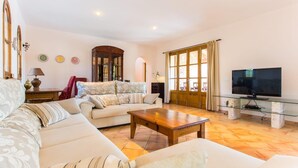 Amplia sala de estar con sofá, una mesa de centro y televisor.
