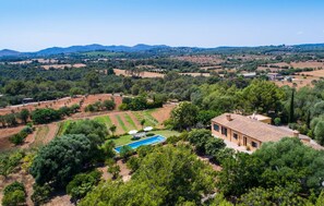 Une villa avec piscine, entourée d’une végétation luxuriante et de champs en terrasses.
