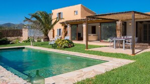 A modern house with a swimming pool, a patio with outdoor furniture, and a mountain backdrop. - Cozy home in Port Verd with private swimming pool, can be inside or outside (Port Verd)