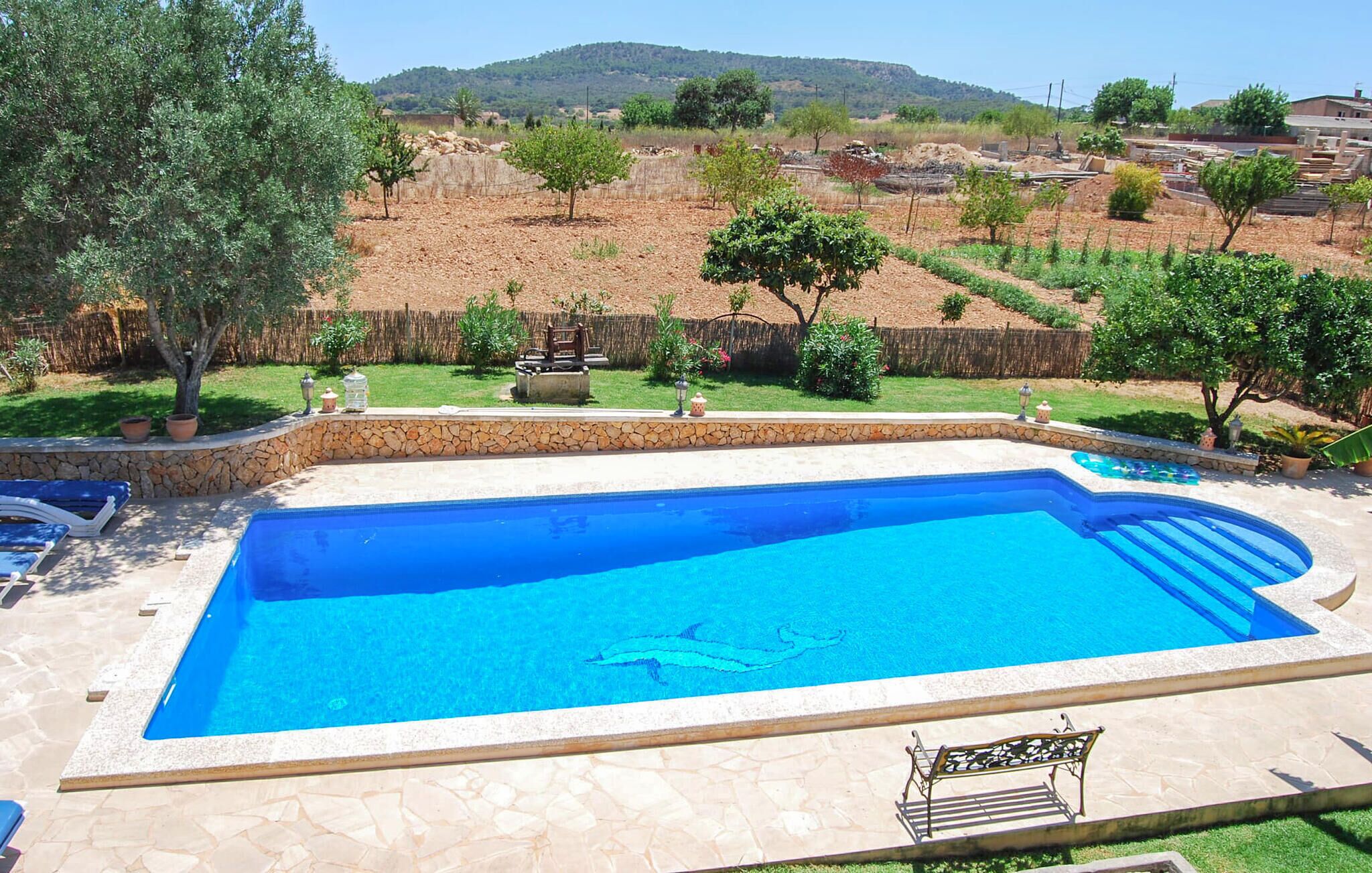 A rectangular swimming pool with a stone border, surrounded by a stone patio.