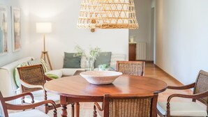 Un comedor con una mesa redonda de madera, sillas de mimbre y una lámpara colgante de fibra.