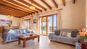A spacious living area with two sofas, a wooden coffee table, and a dining table. Large windows provide a view of the outdoors. - Awesome home in Alqueria Blanca (Alqueria Blanca)