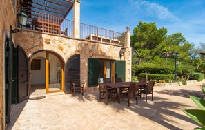 A stone building with a balcony, outdoor seating, and a garden. - Nice home in Porto Colom with private swimming pool, can be inside or outside (Porto Colom)