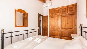 Ein Schlafzimmer mit einem Bett, einem Holzschrank, einem Spiegel und einer Klimaanlage.
