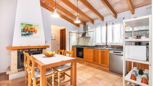 Eine gemütliche Küche mit Holdekor, einem Esstisch mit Stühlen, einem Kamin und einer Kücheninsel mit Spüle und Geschirrspüler.