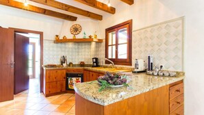 Una cocina con vigas de madera, salpicadero de azulejos, un lavamanos y una cafetera.