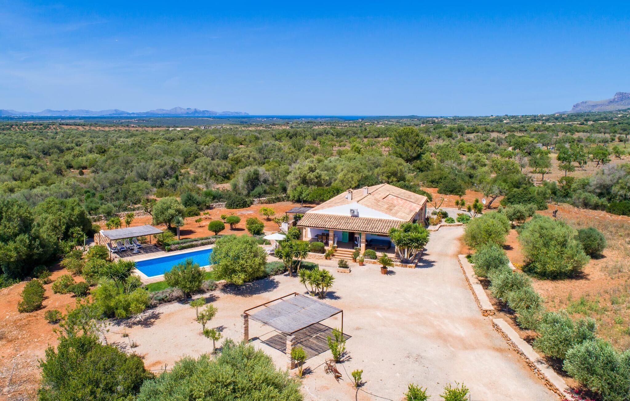 Une villa avec piscine, entourée d’une végétation luxuriante et offrant une vue dégagée sur les montagnes lointaines.