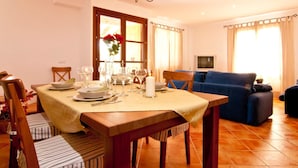 Un coin repas avec une table dressée pour quatre personnes, un canapé et un téléviseur en arrière-plan.