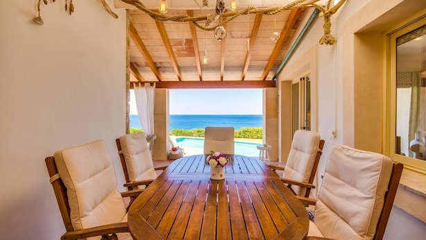 Een houten tafel met vier stoelen in een kamer met uitzicht op de oceaan.