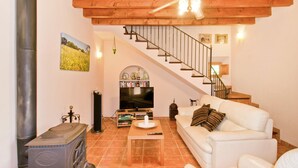 Ein Wohnzimmer mit Kamin, einer Couch, einem Fernseher und einer Treppe.