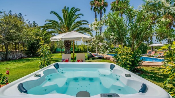 A hot tub in a lush garden with a pool, lounge chairs, and a pergola. - Pet friendly home in Can Picafort (Can Picafort)