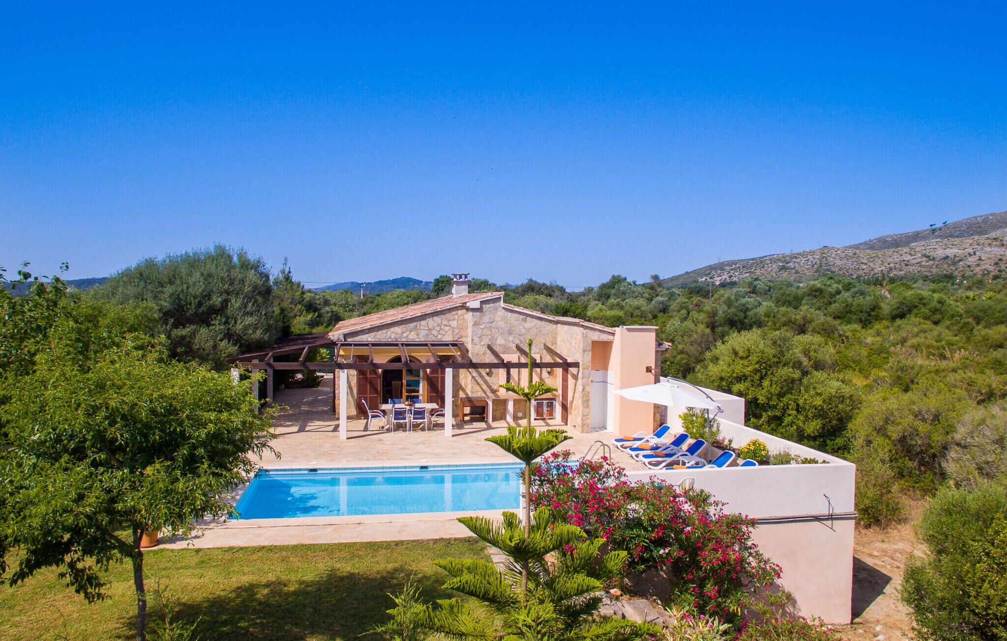 A house with a swimming pool, outdoor seating, and a view of the surrounding landscape.