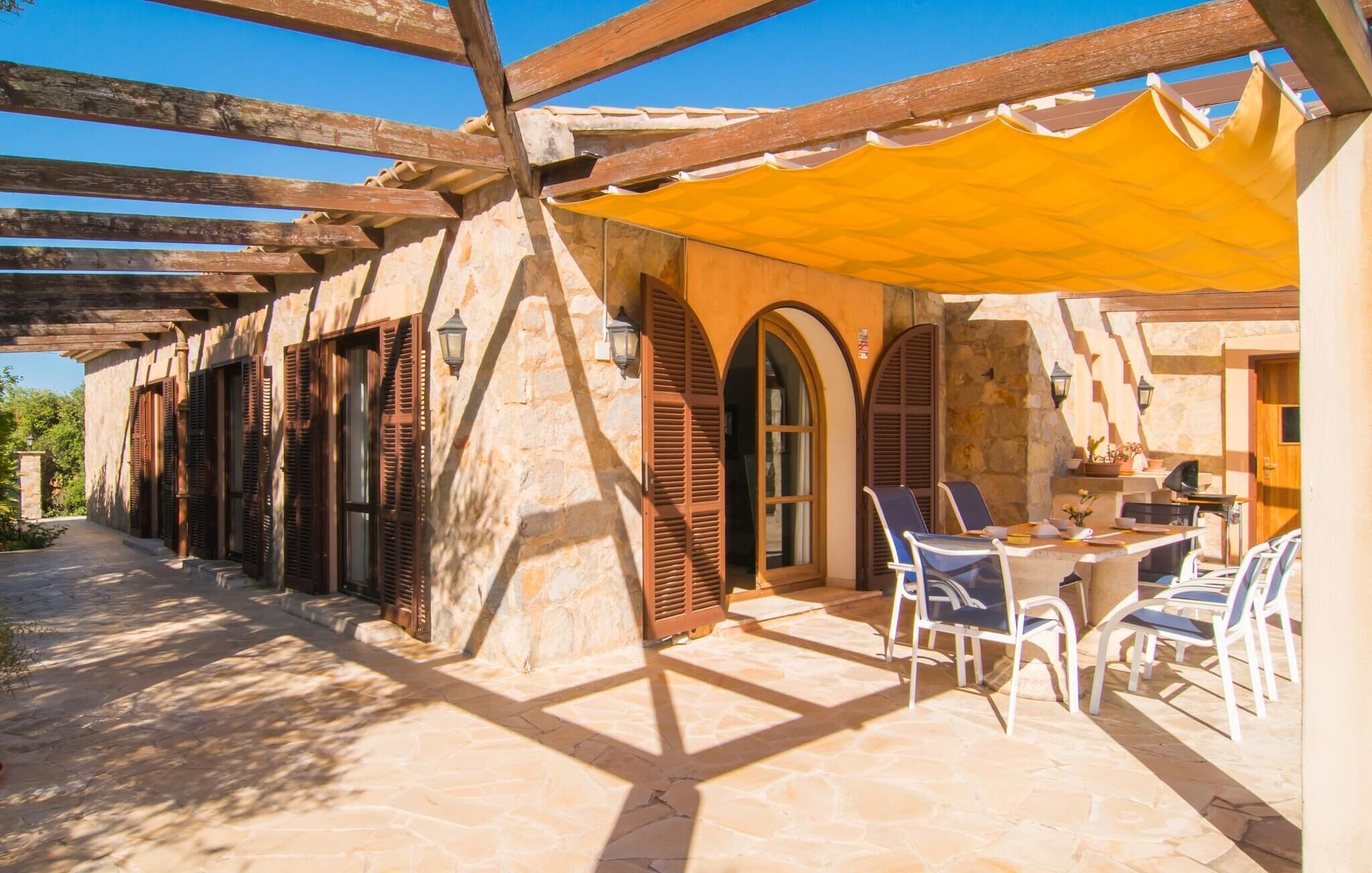 Una zona exterior coberta amb sòl de pedra, bigues de fusta i un aulet groc.