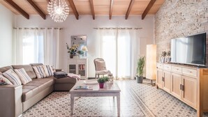 Un salon avec un canapé, une table basse, un téléviseur et un mur en briques.
