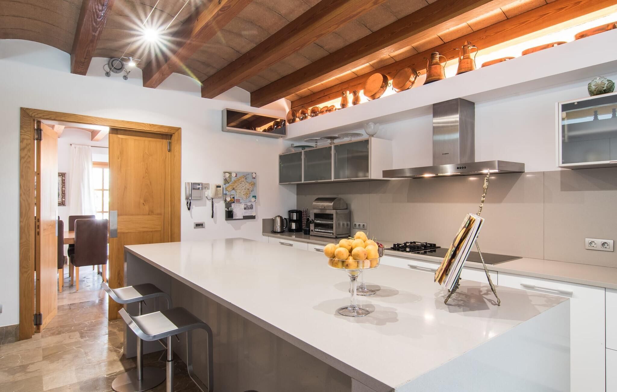 A modern kitchen with a central island, stainless steel appliances, and wooden beams on the ceiling.