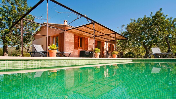 Uma casa com piscina, varanda coberta e móveis de exterior.