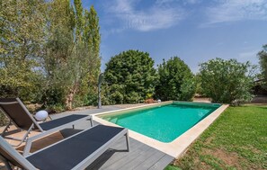 A rectangular swimming pool with a tiled edge, surrounded by a wooden deck. There are lounge chairs with cushions and a white spherical object on the deck. - Lovely home in Inca with private swimming pool, can be inside or outside (Inca)