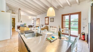 Uma cozinha ampla com uma ilha grande, eletrodomésticos de aço inoxidável e uma luminária pendente.